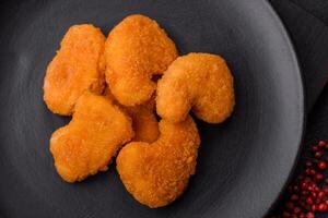 Delicious fresh crispy chicken nuggets on a dark concrete background photo