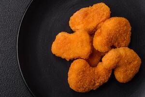 Delicious fresh crispy chicken nuggets on a dark concrete background photo