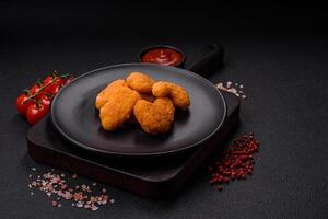 Delicious fresh crispy chicken nuggets on a dark concrete background photo