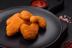 Delicious fresh crispy chicken nuggets on a dark concrete background photo