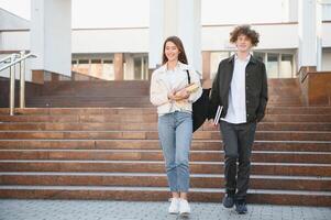 Front view of two students walking and talking in an university campus. photo