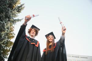 Happy friends on graduation day. Portrait of two cheerful joyful students standing near university building. photo