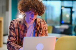 Portrait of cheerful millennial blogger with modern cellphone and laptop technology enjoying freelance lifestyle, happy hipster guy in optical eyewear using mobile phone and netbook in street cafe. photo