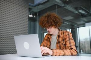 Cheerful male freelancer browsing funny content while networking in social media using netbook technology in street cafe, happy hipster guy enjoying free time for online blogging via laptop photo