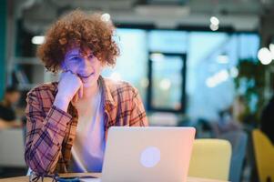 Cheerful male freelancer browsing funny content while networking in social media using netbook technology in street cafe, happy hipster guy enjoying free time for online blogging via laptop photo