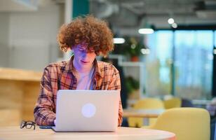 Cheerful male freelancer browsing funny content while networking in social media using netbook technology in street cafe, happy hipster guy enjoying free time for online blogging via laptop photo