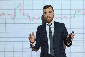 Man is standing near projector and showing graphs and business graphs. photo