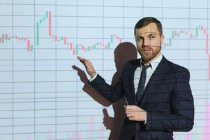 Man is standing near projector and showing graphs and business graphs. photo