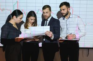 Group of business people working at modern office.Technical price graph, red and blue candlestick chart and stock trading computer screen background. Double exposure. Traders analyzing data photo