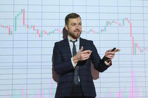 Young Businessman Explaining Graphs To His Colleagues On Projector photo