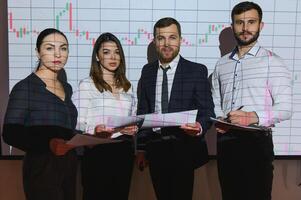 Group of business people working at modern office.Technical price graph, red and blue candlestick chart and stock trading computer screen background. Double exposure. Traders analyzing data photo