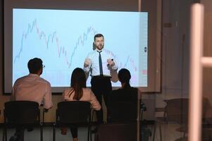 Man is standing near projector and showing graphs and business graphs. photo