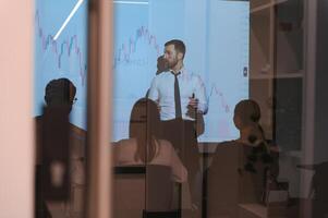 Man is standing near projector and showing graphs and business graphs. photo