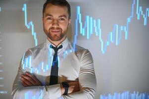 Stock Market Top Trader Looks at Projected Ticker Numbers and Graphs Running, Analysing Data to Make Best Sell. Behind Him Room Full of Screens and Statistics. photo