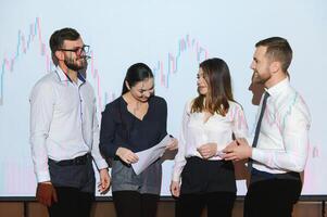 Group of business people working at modern office.Technical price graph, red and blue candlestick chart and stock trading computer screen background. Double exposure. Traders analyzing data photo