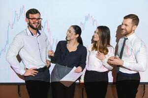 Group of business people working at modern office.Technical price graph, red and blue candlestick chart and stock trading computer screen background. Double exposure. Traders analyzing data photo