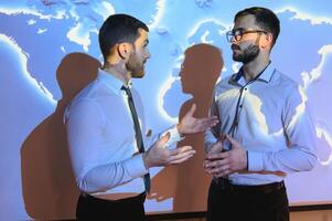 Two Business Colleagues Have Informal Meeting On Stairs Of Office With World Map In Background photo