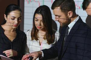 Business Conference Meeting Presentation. Businessman does Financial Analysis talks to Group of Businessspeople. Projector Screen Shows Stock Market Data, Investment Strategy, Revenue Growth photo