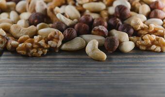 mixed nuts in a bowl on wooden table, top view with copy space. photo