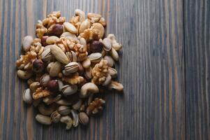 mixed nuts in a bowl on wooden table, top view with copy space. photo