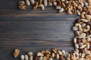 mixed nuts in a bowl on wooden table, top view with copy space. photo