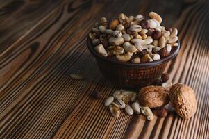 mixed nuts in a bowl on wooden table, top view with copy space. photo