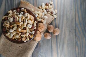 mixed nuts in a bowl on wooden table, top view with copy space. photo
