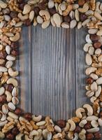 mixed nuts in a bowl on wooden table, top view with copy space. photo