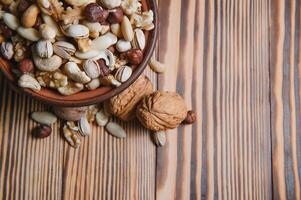 mixed nuts in a bowl on wooden table, top view with copy space. photo
