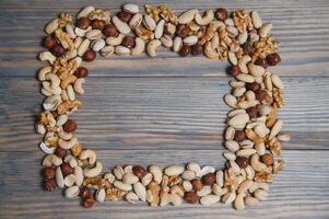 mixed nuts in a bowl on wooden table, top view with copy space. photo