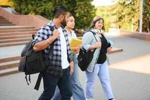 Portrait of three multi-ethnic university students embracing together standing in the campus photo