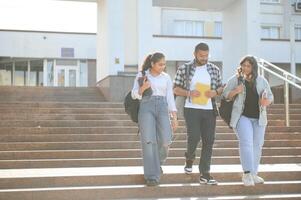 Portrait of three multi-ethnic university students embracing together standing in the campus photo