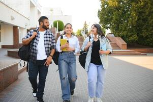 Portrait of three multi-ethnic university students embracing together standing in the campus photo