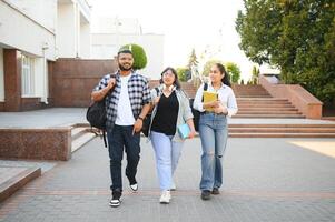 Portrait of three multi-ethnic university students embracing together standing in the campus photo