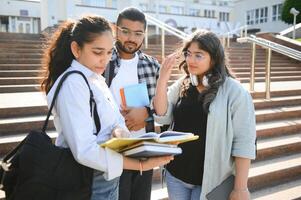 Portrait of three multi-ethnic university students embracing together standing in the campus photo