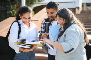 Portrait of three multi-ethnic university students embracing together standing in the campus photo