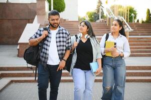 Three international students standing and holding a books photo