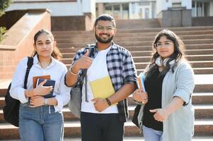 Portrait of three multi-ethnic university students embracing together standing in the campus photo