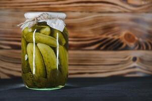 Canned cucumbers and tomatoes with craft lids on a wooden background. Cucumbers and tomatoes with place for text. Stocks of canned food. Harvest, stocks for the winter. photo