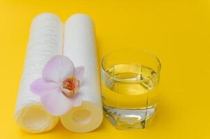 Water filters. Carbon cartridges and a glass on a yellow background. Household filtration system photo