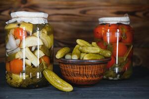 Jars of pickled vegetables on rustic wooden background photo