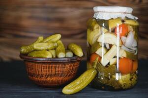 Pickled gherkins or cucumbers in bowl on wooden rustic table from above. photo