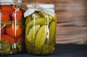 Jars of pickled vegetables on rustic wooden background photo