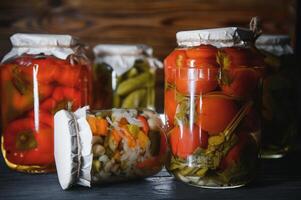 Canned cucumbers and tomatoes with craft lids on a wooden background. Cucumbers and tomatoes with place for text. Stocks of canned food. Harvest, stocks for the winter. photo