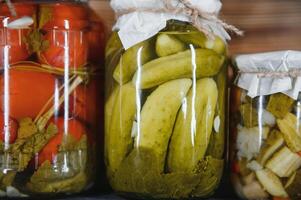 Canned cucumbers and tomatoes with craft lids on a wooden background. Cucumbers and tomatoes with place for text. Stocks of canned food. Harvest, stocks for the winter. photo