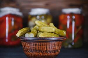Jars of pickled vegetables on rustic wooden background photo