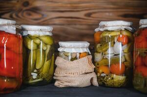 Jars of pickled vegetables on rustic wooden background photo