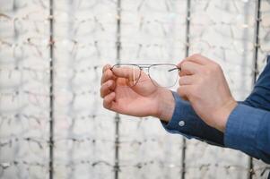 Man evaluating quality of glasses in optical shop photo