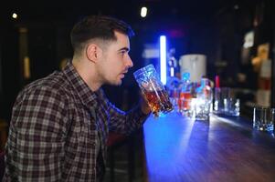 Handsome bearded man drinking beer at the bar counter in pub photo