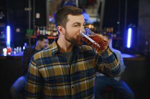 Tasting a good beer. Portrait of thoughtful men drinking beer at the bar photo